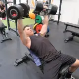 Mann macht incline bench press mit schweren Hanteln.
