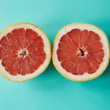 Zwei Hälften einer Grapefruit auf türkisfarbenem Hintergrund. Grapefruit ist ein Obst, in dem viel Calcium ist.