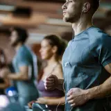 Sportler auf Laufbändern im Fitnessstudio, die auf ihren anaeroben Training Puls achten.