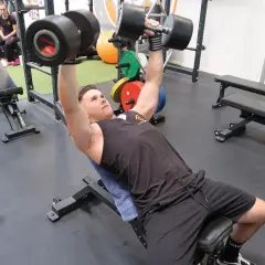 Mann macht incline bench press mit schweren Hanteln.
