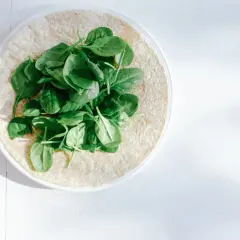 Frischer Spinat auf einem Tortilla-Wrap. Eine gesunde Mahlzeit, die viel Lutein liefert.