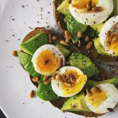 Avocado-Toast mit Ei und Pinienkernen. Eier sind gute Vitamin B9 Lebensmittel.