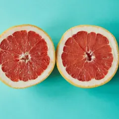 Zwei Hälften einer Grapefruit auf türkisfarbenem Hintergrund. Grapefruit ist ein Obst, in dem viel Calcium ist.