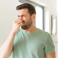 Mann hält sich die Nase zu, weil es stinkt. Ob pupsen gesund ist, bleibt fraglich.