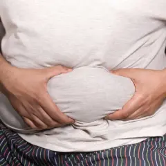 Mann mit Bauchansatz greift sich an den Bauch. Mögliche erektionsprobleme mit 50?
