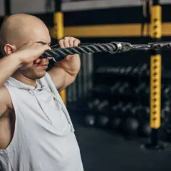 Mann macht Face Pulls am Kabelzug im Fitnessstudio.