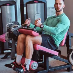 Mann trainiert Beine an einem Gerät für **leg curls**.