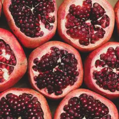 Viele aufgeschnittene Granatäpfel mit leuchtend roten Kernen. Ein wahrhaft **granatapfel gesund** Genuss für Körper und Seele.