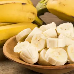 Ein Haufen reifer Bananen, einige im Ganzen, andere in Scheiben in einer Holzschale. Eine Banane enthält viel Kalium.