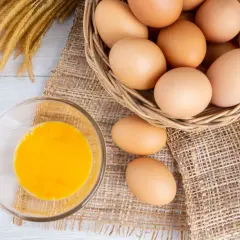 Eier in einem Korb und ein Glas Eigelb. Eine **Eier Vitamine Tabelle** könnte diese Nährstoffe detailliert auflisten.