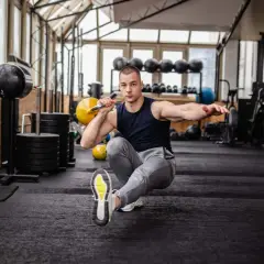 Mann macht einen Pistol Squat mit Kettlebell im Fitnessstudio.