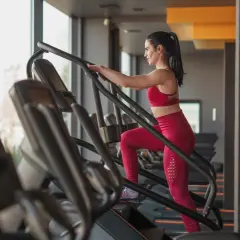 Frau trainiert auf einem Treppensteiger im Fitnessstudio. Was bringt Treppensteigen? Es stärkt Beine und Po, verbessert die Ausdauer und verbrennt Kalorien.