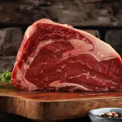 Ein saftiges Stück rotes Fleisch, reich an Eisen, liegt auf einem Holzbrett. Daneben Kräuter und Gewürze.