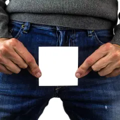 Mann hält ein weißes Blatt Papier vor sich, das eine Beule am Penis verdeckt.