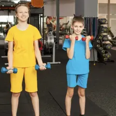 Zwei Kinder trainieren im Fitnessstudio mit Hanteln. Ab wie vielen Jahren darf man ins Gym? Hier wird gezeigt, dass auch junge Leute fit werden können!