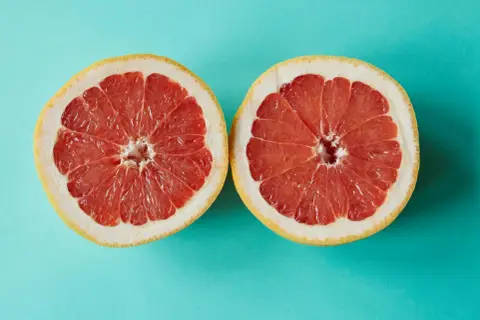 Zwei Hälften einer Grapefruit auf türkisfarbenem Hintergrund. Grapefruit ist ein Obst, in dem viel Calcium ist.
