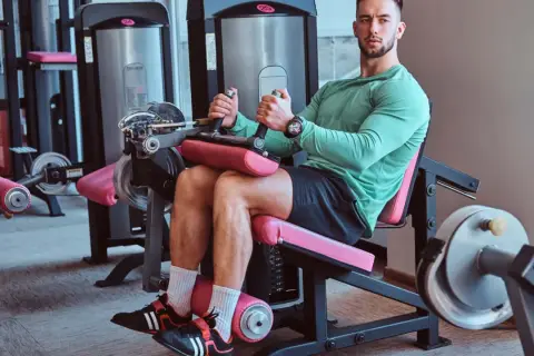 Mann trainiert Beine an einem Gerät für **leg curls**.