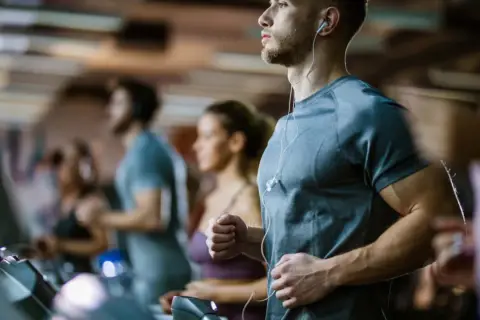 Sportler auf Laufbändern im Fitnessstudio, die auf ihren anaeroben Training Puls achten.