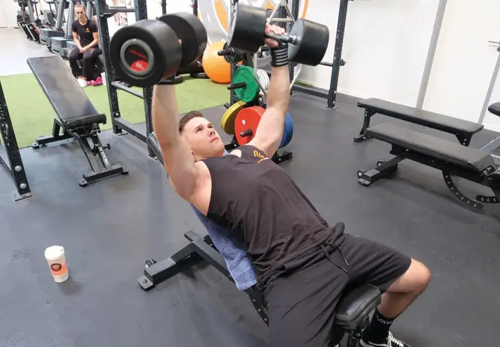 Mann macht incline bench press mit schweren Hanteln.