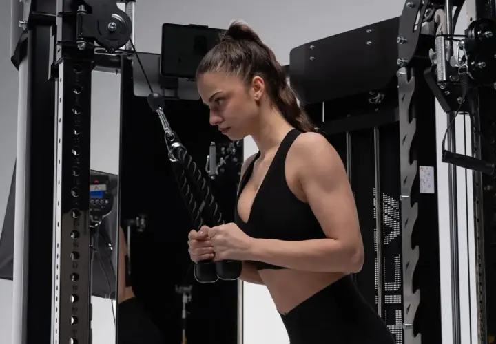 Frau macht Hammer Curls am Kabelzug. Konzentriert sich auf die Bewegung, um die Armmuskulatur zu stärken.