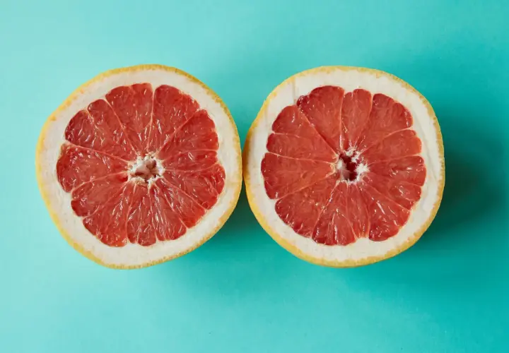 Zwei Hälften einer Grapefruit auf türkisfarbenem Hintergrund. Grapefruit ist ein Obst, in dem viel Calcium ist.