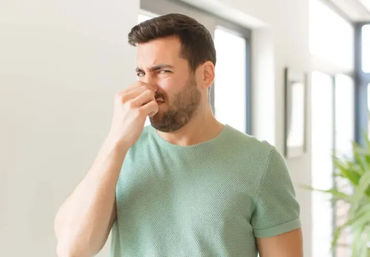 Mann hält sich die Nase zu, weil es stinkt. Ob pupsen gesund ist, bleibt fraglich.