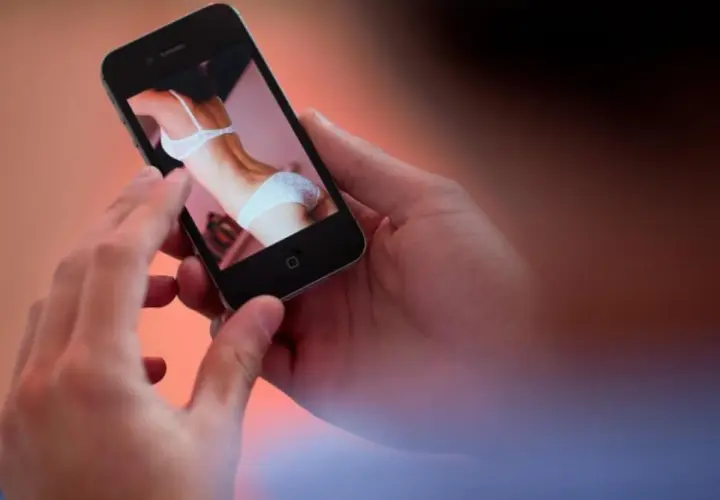 Hände halten ein Smartphone, das ein Bild einer Frau in Unterwäsche zeigt. Ein Moment der Versuchung, der die Kraft des "no fap" unterstreicht.