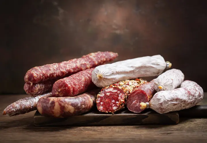 Ein Haufen verschiedener Salamisorten, von denen einige mit Gewürzen bedeckt sind. Die Frage, ob **ist schweinefleisch ungesund**, bleibt bei dieser appetitlichen Auswahl offen.