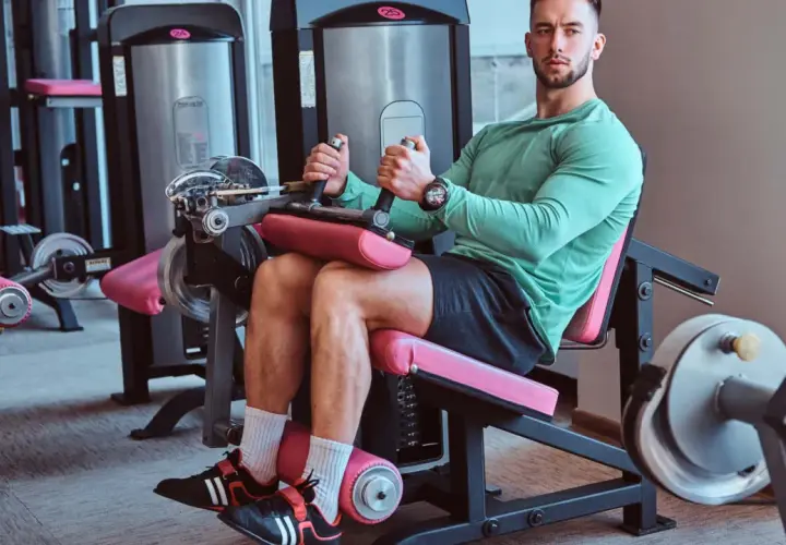 Mann trainiert Beine an einem Gerät für **leg curls**.