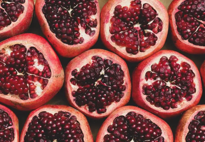 Viele aufgeschnittene Granatäpfel mit leuchtend roten Kernen. Ein wahrhaft **granatapfel gesund** Genuss für Körper und Seele.