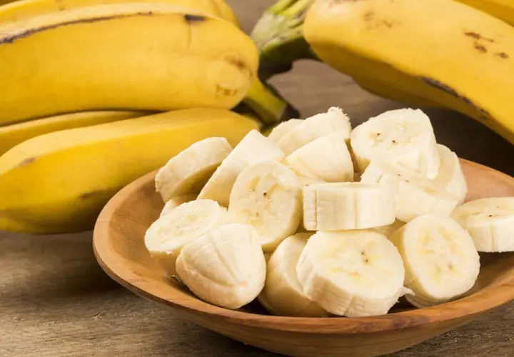Ein Haufen reifer Bananen, einige im Ganzen, andere in Scheiben in einer Holzschale. Eine Banane enthält viel Kalium.