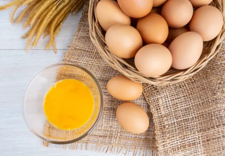 Eier in einem Korb und ein Glas Eigelb. Eine **Eier Vitamine Tabelle** könnte diese Nährstoffe detailliert auflisten.