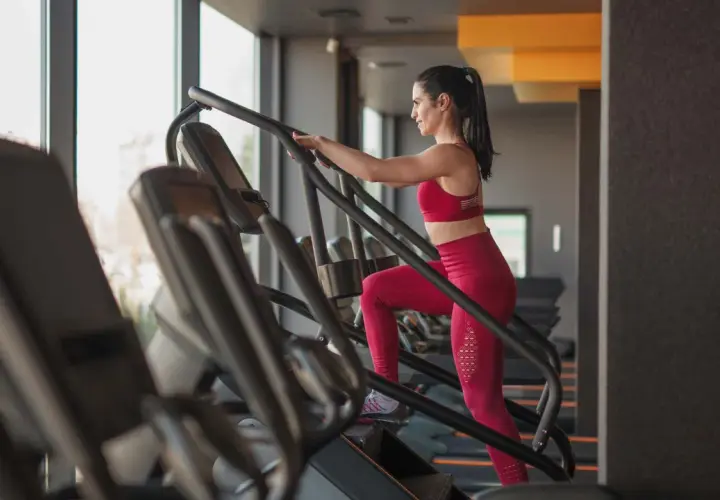 Frau trainiert auf einem Treppensteiger im Fitnessstudio. Was bringt Treppensteigen? Es stärkt Beine und Po, verbessert die Ausdauer und verbrennt Kalorien.