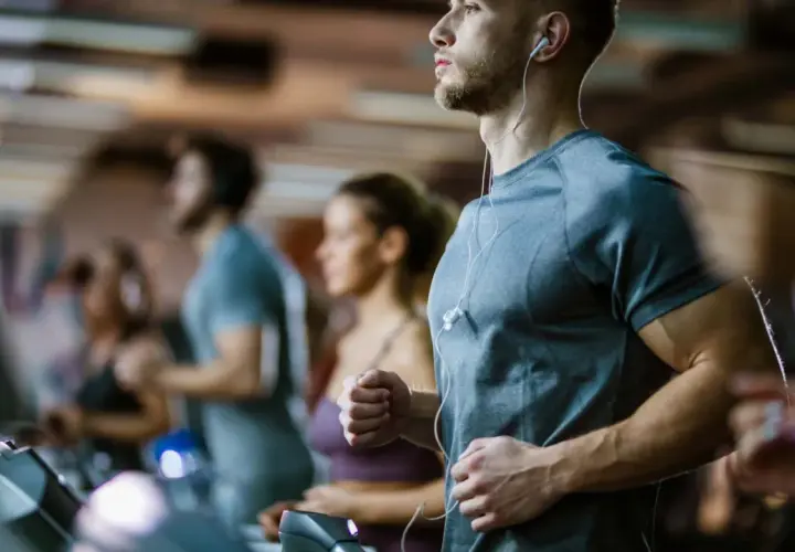 Sportler auf Laufbändern im Fitnessstudio, die auf ihren anaeroben Training Puls achten.