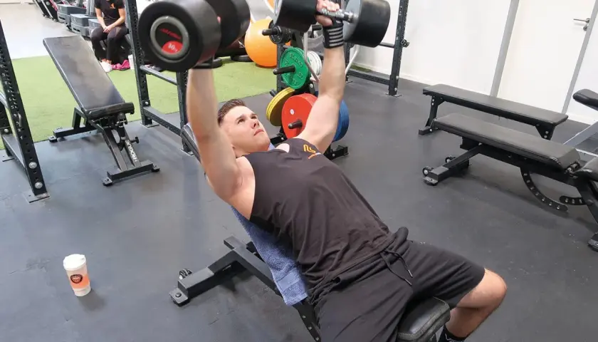 Mann macht incline bench press mit schweren Hanteln.