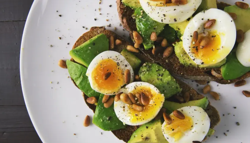 Avocado-Toast mit Ei und Pinienkernen. Eier sind gute Vitamin B9 Lebensmittel.