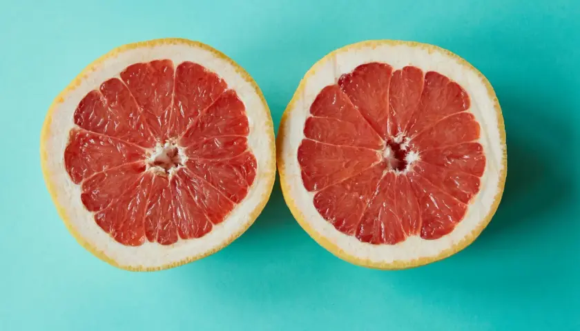 Zwei Hälften einer Grapefruit auf türkisfarbenem Hintergrund. Grapefruit ist ein Obst, in dem viel Calcium ist.