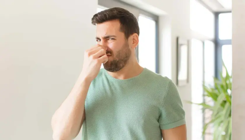 Mann hält sich die Nase zu, weil es stinkt. Ob pupsen gesund ist, bleibt fraglich.