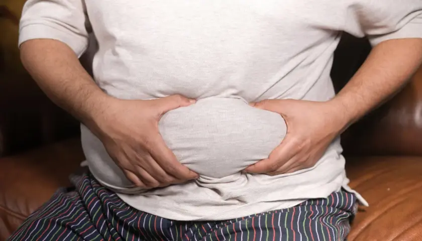 Mann mit Bauchansatz greift sich an den Bauch. Mögliche erektionsprobleme mit 50?