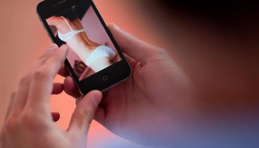 Hände halten ein Smartphone, das ein Bild einer Frau in Unterwäsche zeigt. Ein Moment der Versuchung, der die Kraft des "no fap" unterstreicht.