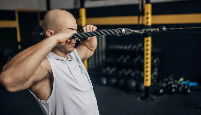 Mann macht Face Pulls am Kabelzug im Fitnessstudio.