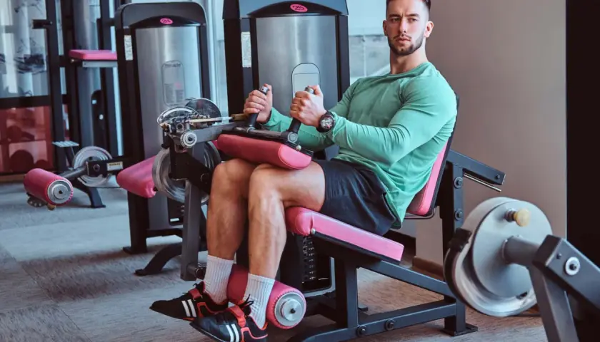 Mann trainiert Beine an einem Gerät für **leg curls**.
