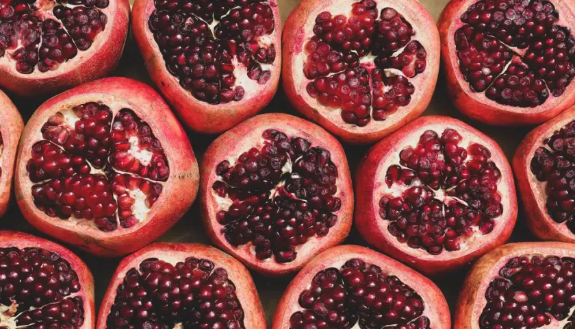 Viele aufgeschnittene Granatäpfel mit leuchtend roten Kernen. Ein wahrhaft **granatapfel gesund** Genuss für Körper und Seele.