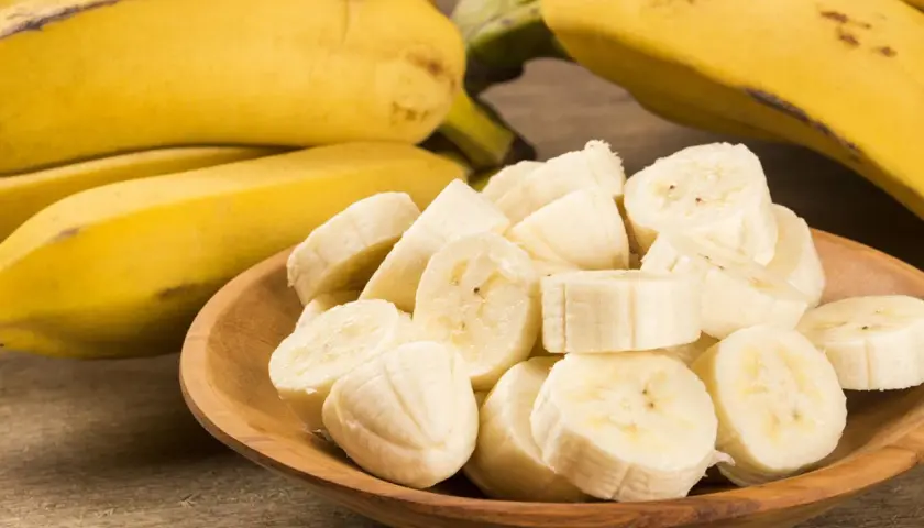 Ein Haufen reifer Bananen, einige im Ganzen, andere in Scheiben in einer Holzschale. Eine Banane enthält viel Kalium.