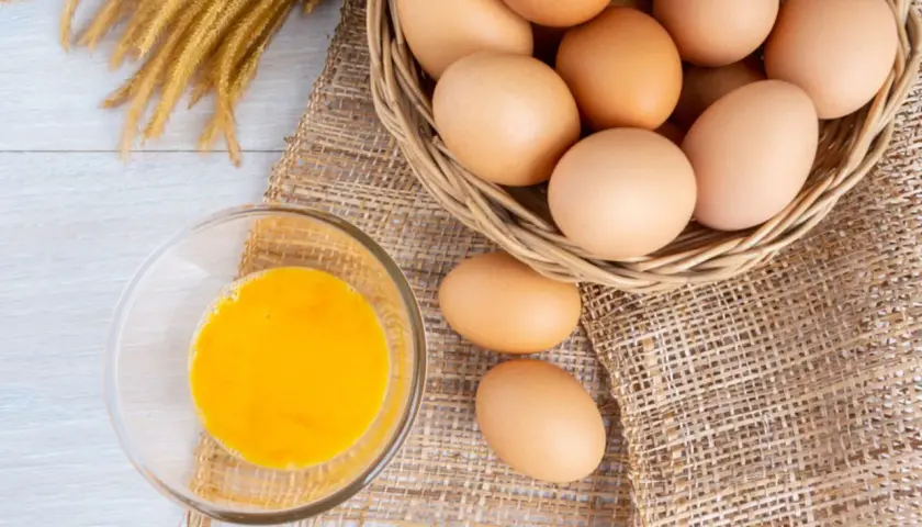Eier in einem Korb und ein Glas Eigelb. Eine **Eier Vitamine Tabelle** könnte diese Nährstoffe detailliert auflisten.