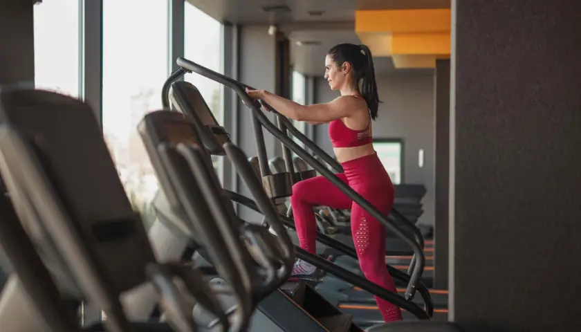 Frau trainiert auf einem Treppensteiger im Fitnessstudio. Was bringt Treppensteigen? Es stärkt Beine und Po, verbessert die Ausdauer und verbrennt Kalorien.