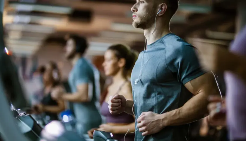 Sportler auf Laufbändern im Fitnessstudio, die auf ihren anaeroben Training Puls achten.