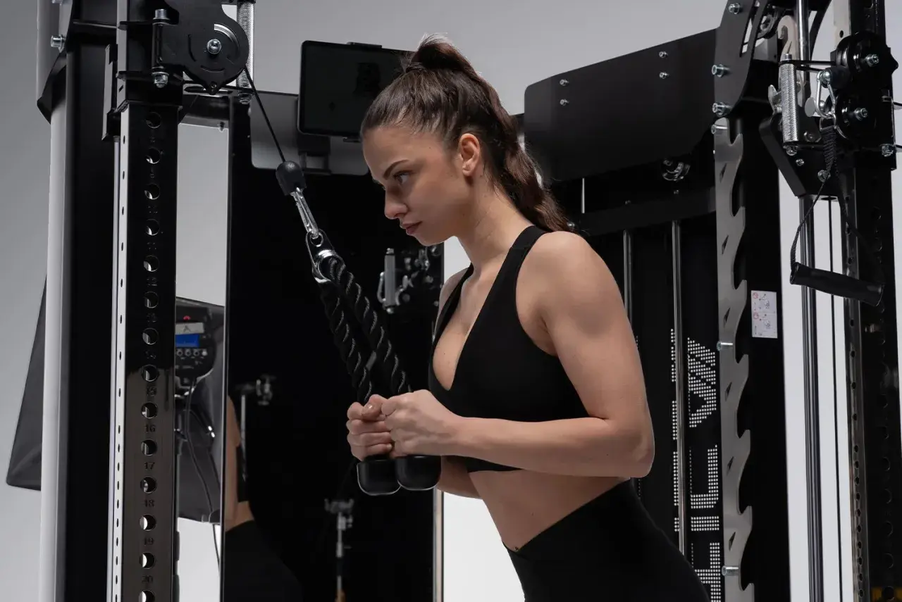 Frau macht Hammer Curls am Kabelzug. Konzentriert sich auf die Bewegung, um die Armmuskulatur zu stärken.