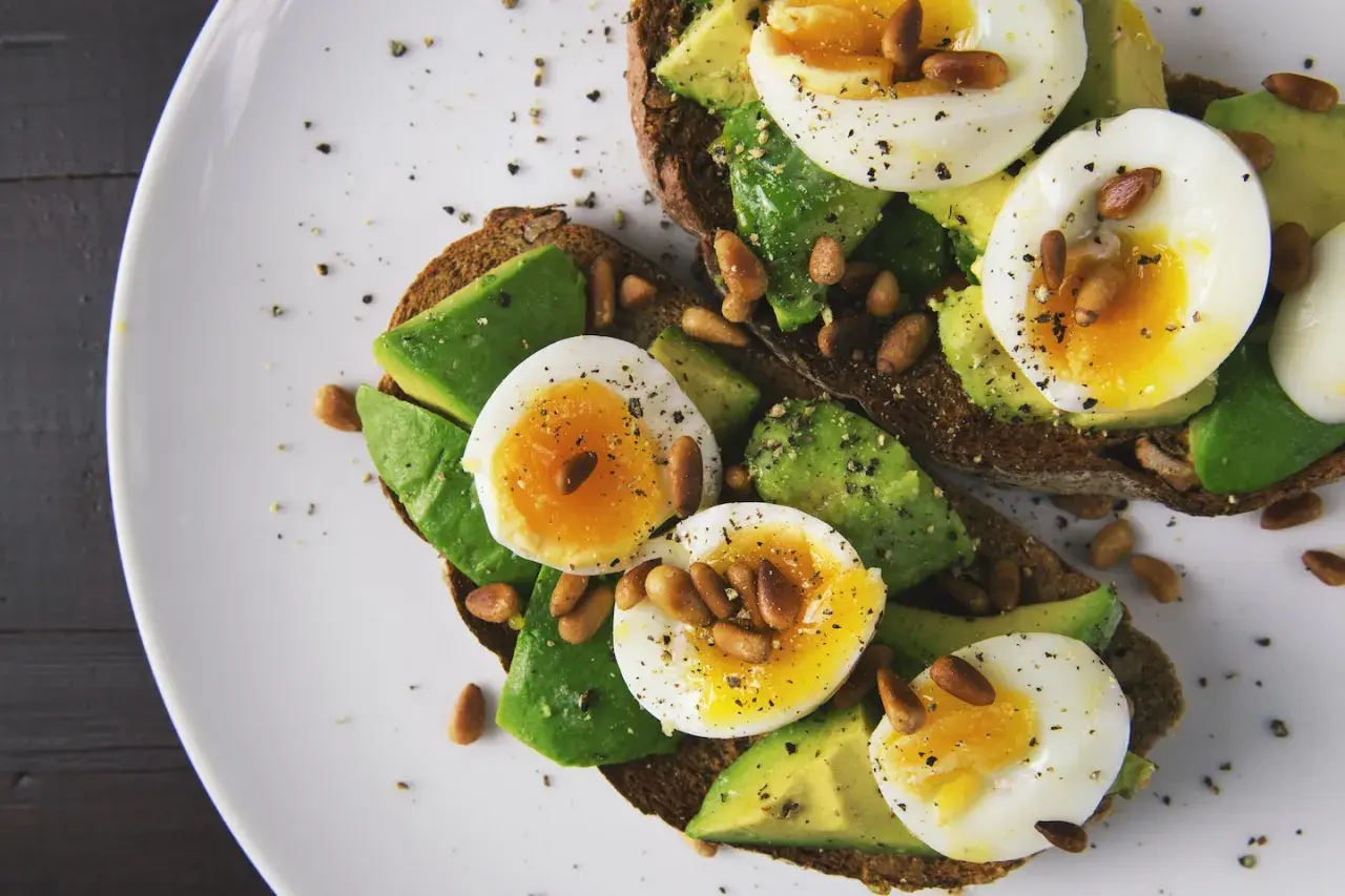 Avocado-Toast mit Ei und Pinienkernen. Eier sind gute Vitamin B9 Lebensmittel.