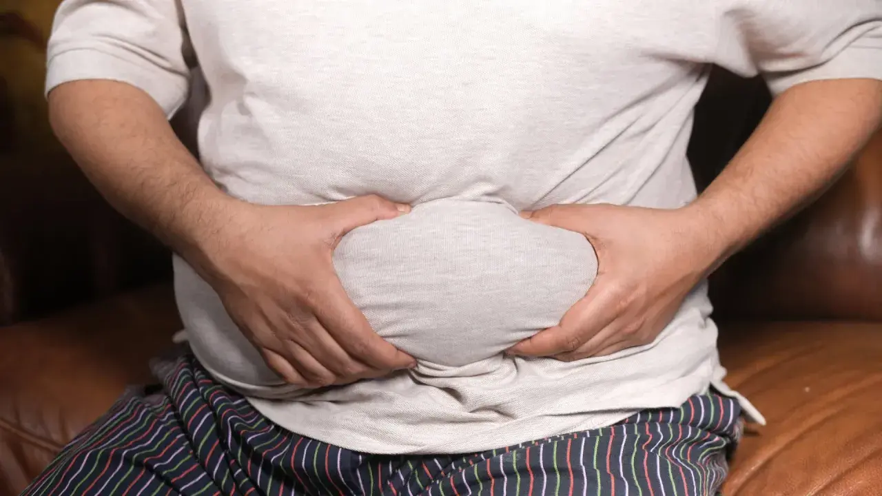 Mann mit Bauchansatz greift sich an den Bauch. Mögliche erektionsprobleme mit 50?